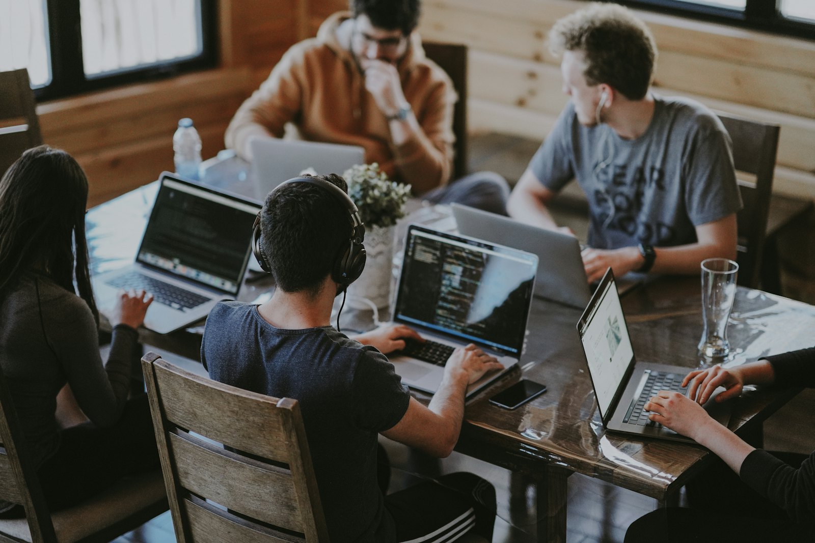 An engineering team working together around a table of laptops.